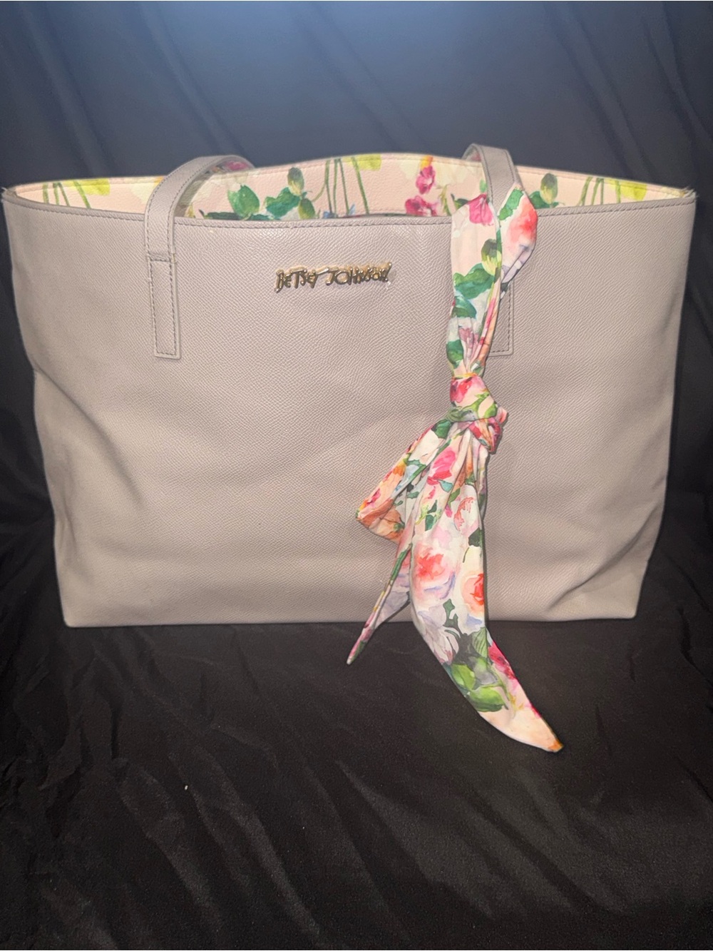 A grey Betsey Johnson XO Zaria Tote accented with a colorful scarf.